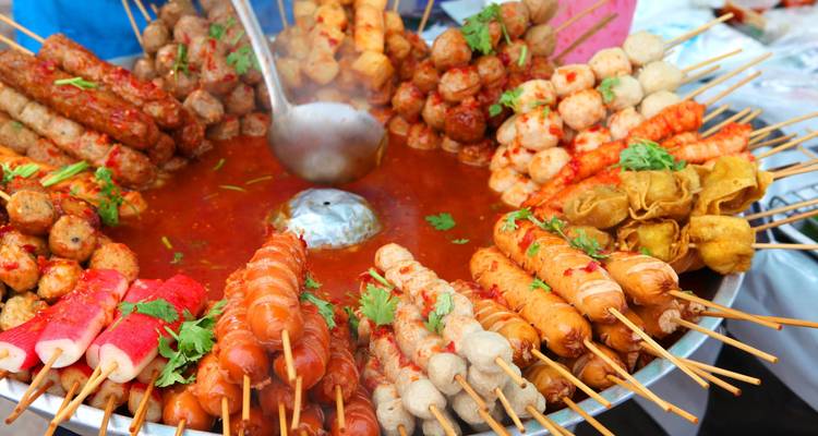 Colorful skewers of grilled food in a vibrant street market.