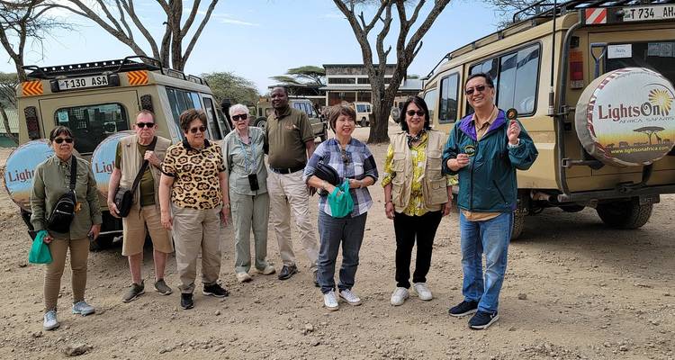 Eine Gruppe von Touristen, die vor Safari-Fahrzeugen steht.