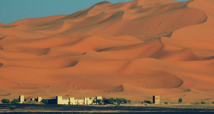 Dunes du désert du Sahara avec un bâtiment au premier plan.