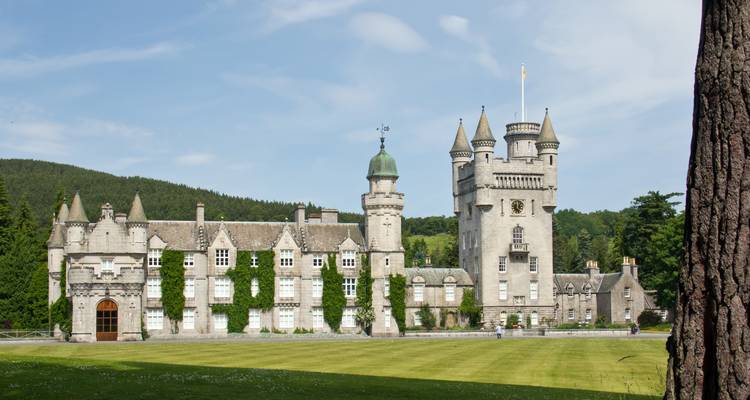 Elegant Balmoral Castle with ivy-clad walls set against wooded Highlands