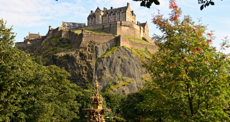 Iconic Edinburgh Castle perched atop volcanic crag framed by leafy park