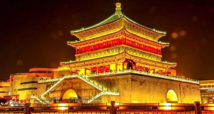 De Belletoren van Xi'an gloedt goudkleurig onder de nachtverlichting met sterretjeseffecten op de trappen eromheen.