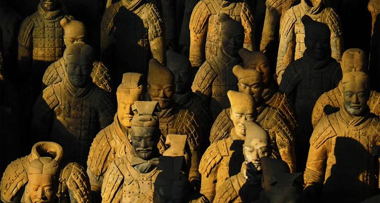Close-up view of rows of the Terracotta Warriors statues with dramatic lighting highlighting their detailed armor and facial features.