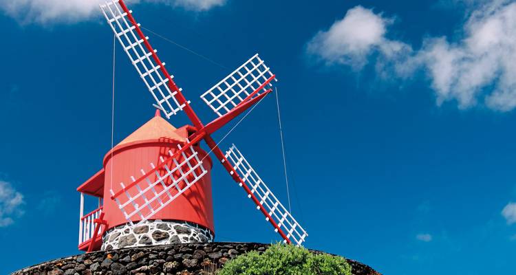 Eine traditionelle rote Windmühle vor einem strahlend blauen Himmel.
