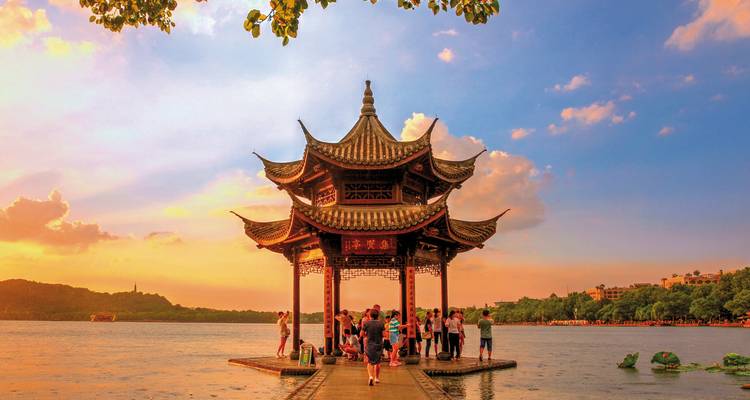 Pagoda by a lake at sunset with people gathered