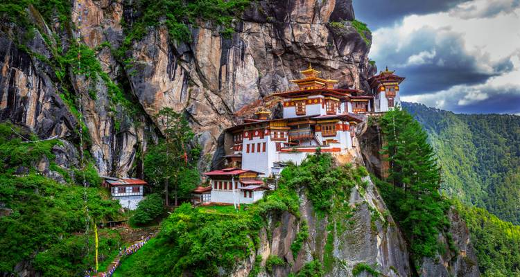 Das Tigernest-Kloster, das in die Seite eines Berges gebaut wurde, mit Grün rundherum.