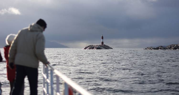 Des gens sur un bateau regardant un phare au loin.