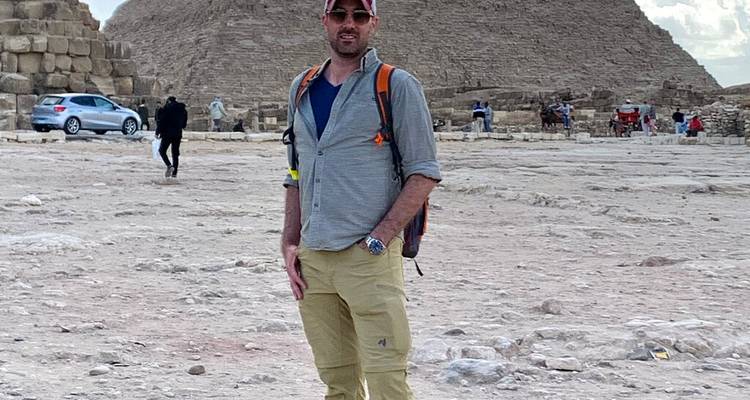 Homme posant avec le bras tendu devant une pyramide