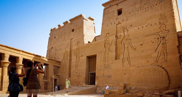 Touristes prenant des photos de reliefs de temple égyptien antique.