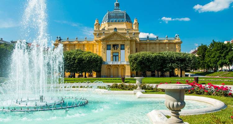 Palacio con fuente y jardines en primer plano.