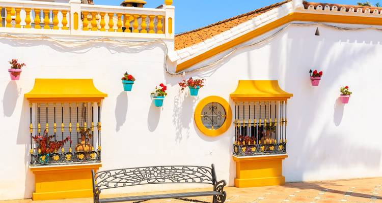 Fachada colorida con flores y bancos, arquitectura típica