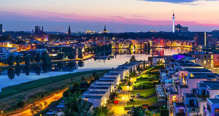 Night view of a city with illuminated architecture and waterfront.