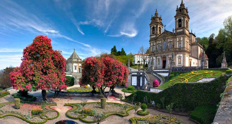 Historischer Garten und barocke Kirche mit blühenden Bäumen.