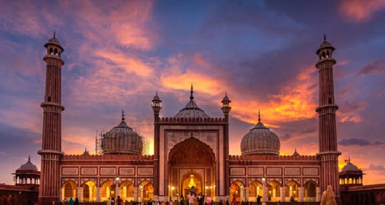 A grand mosque with domes and minarets at sunset.