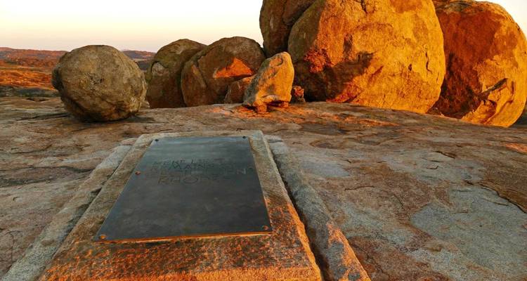 Une plaque commémorative sur un paysage rocheux au coucher du soleil.