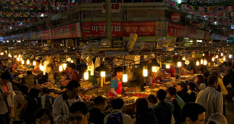 Escena bulliciosa de mercado con luces vibrantes y gente comprando.