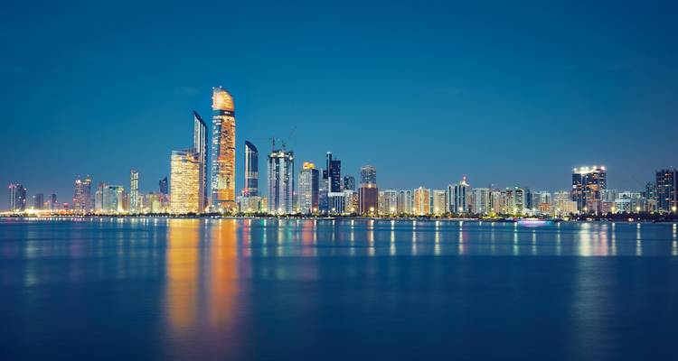 Nachtansicht einer Stadtskyline mit Spiegelungen auf dem Wasser.