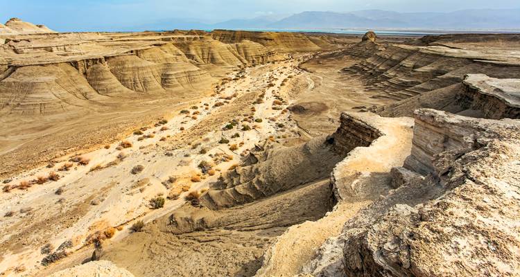 A vast desert landscape with rugged hills and a winding path.