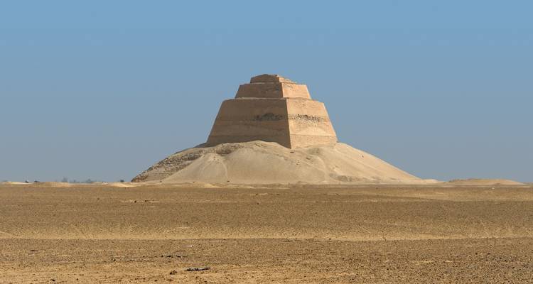 Une pyramide dans un paysage désertique sous un ciel bleu clair.