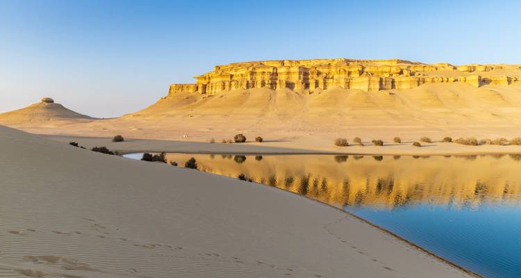 Un paysage désertique avec un plan d'eau reflétant les falaises.