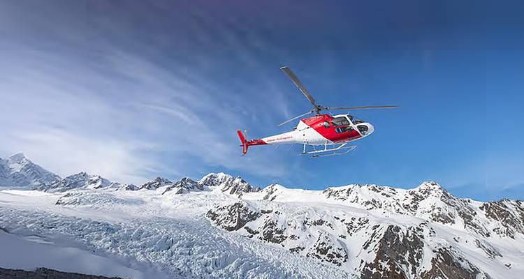 Un hélicoptère volant au-dessus de montagnes enneigées.