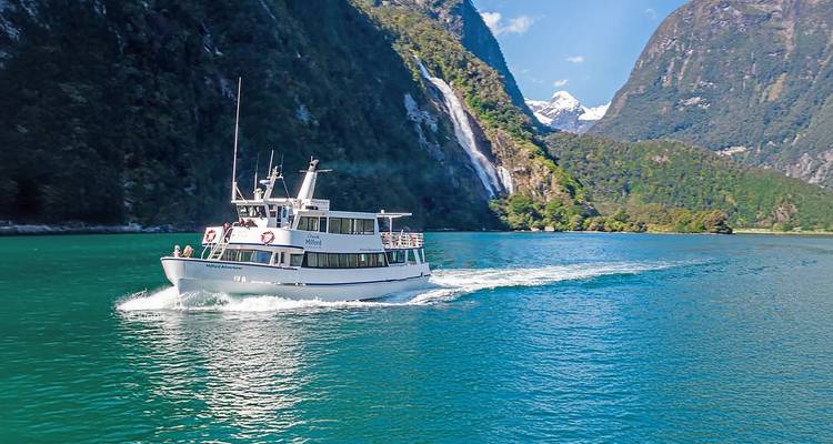 Un bateau naviguant sur un lac turquoise avec une cascade à proximité.
