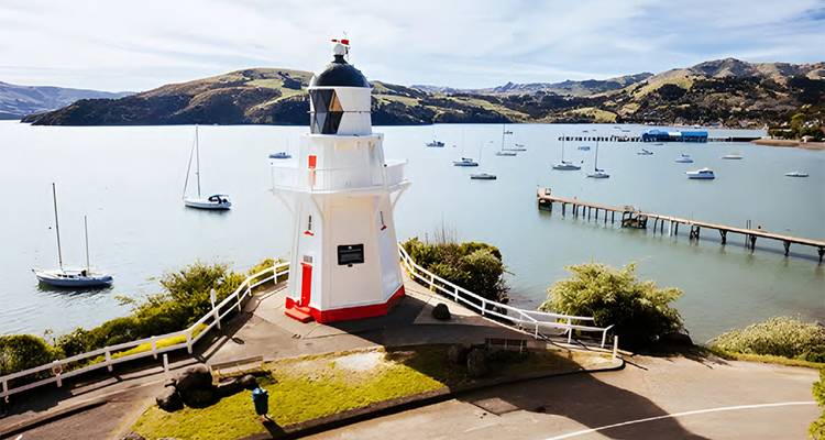 Un phare surplombant une baie avec des bateaux et des collines.
