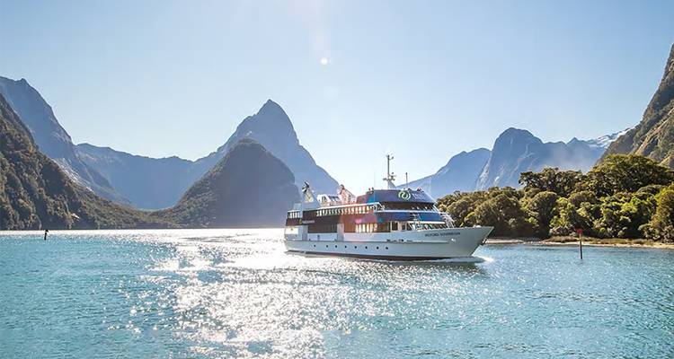 Un bateau de croisière dans un fjord pittoresque entouré de sommets.