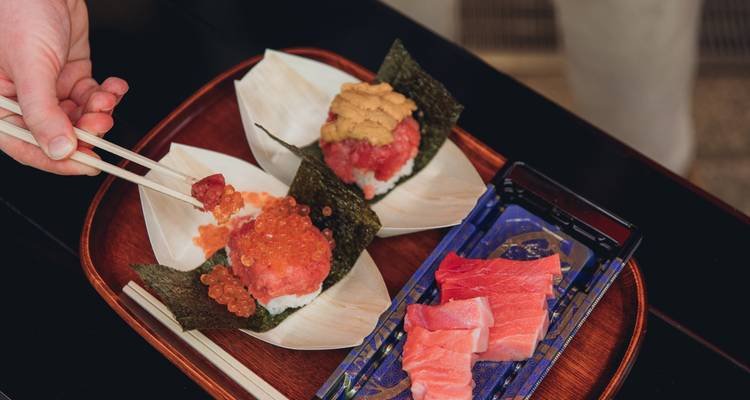 Gros plan de sushis avec algues et baguettes sur un plateau.