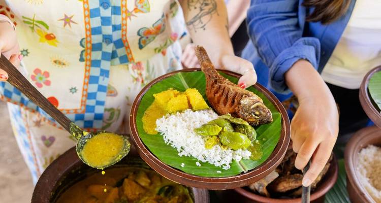 Handen die een traditioneel Sri Lankaans currygerecht serveren op bananenblad met rijst en groenten
