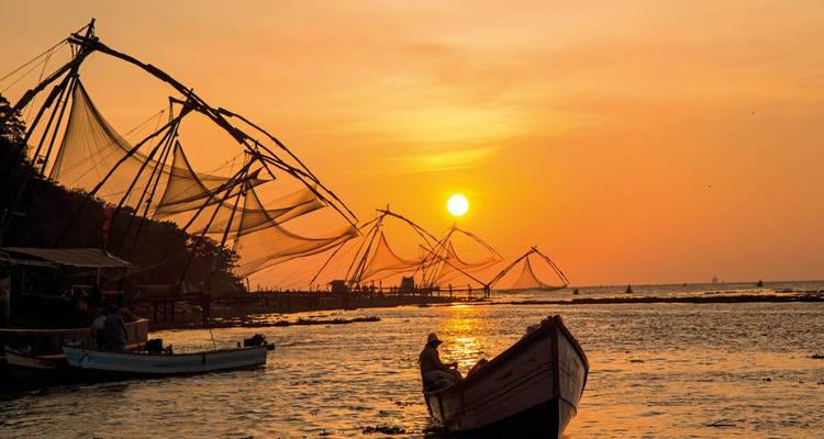 Fischer auf einem Boot mit chinesischen Fischernetzen bei Sonnenuntergang