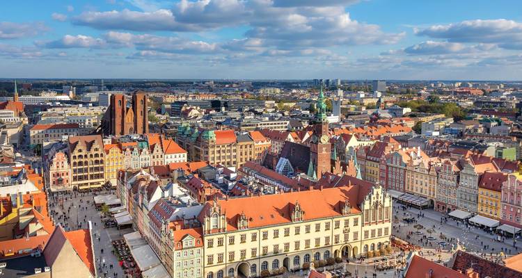 Panorama aérea de la plaza mayor de Wroclaw con casas de colores, torres de iglesias góticas y multitudes de gente animada.