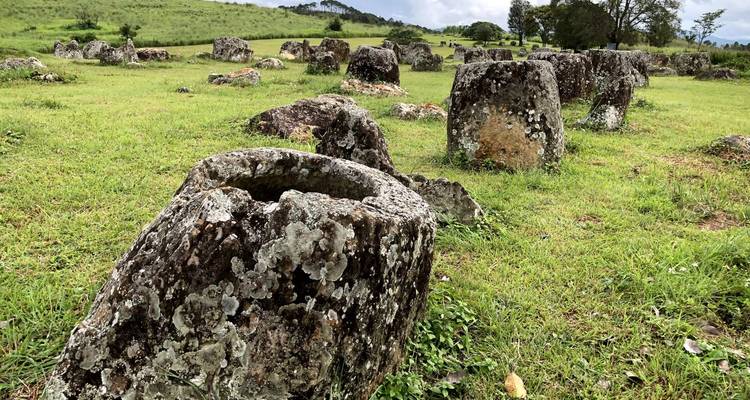 Een landschap met grote oude stenen kruiken op groen gras.