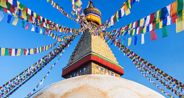 Stupa met kleurrijke gebedsvlaggen onder een blauwe hemel.