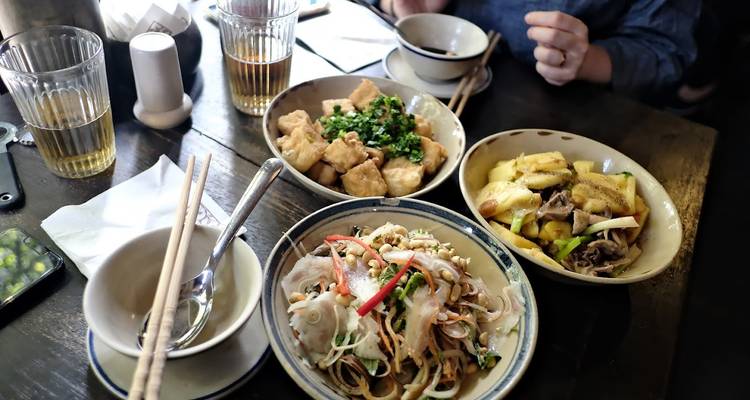 Tabletop spread of Vietnamese dishes including noodles, tofu and vegetables ready for tasting.