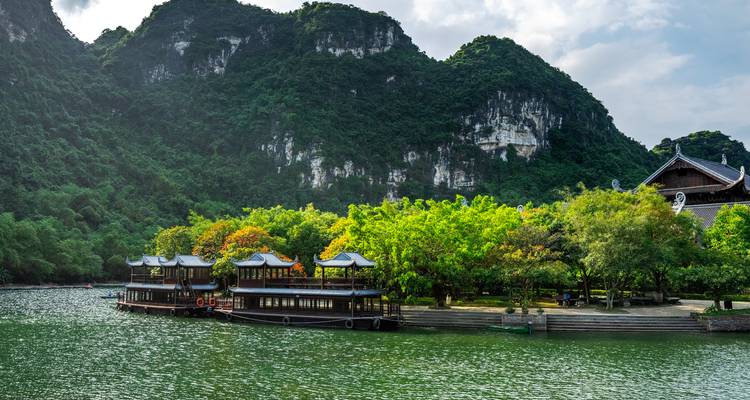 Tranquil lakeside pavilions backed by dramatic limestone karst cliffs and dense jungle in Ninh Binh.