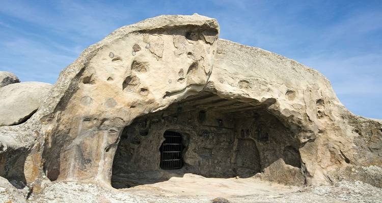 Entrée de grotte rocheuse avec gravures historiques à l'intérieur.