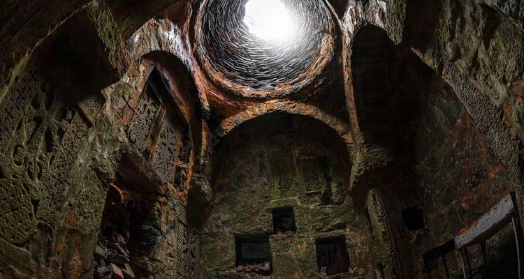 Intérieur d'un dôme avec des sculptures en pierre complexes et une ouverture au sommet.