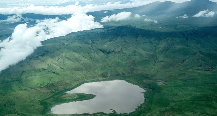 Luftaufnahme eines Kratersees umgeben von üppigen Hügeln.