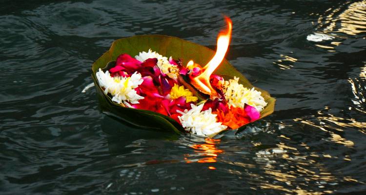 Feuille flottante avec des fleurs et une bougie allumée sur l'eau.