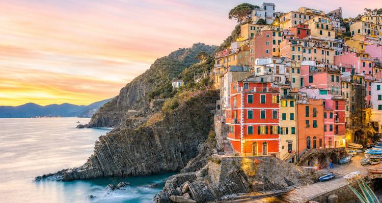 Kleurig dorpje aan de klif van Riomaggiore in Cinque Terre bij zonsondergang boven de glimmende zee