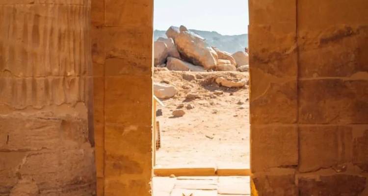 Une vue à travers une ancienne porte en pierre montrant un paysage rocheux.