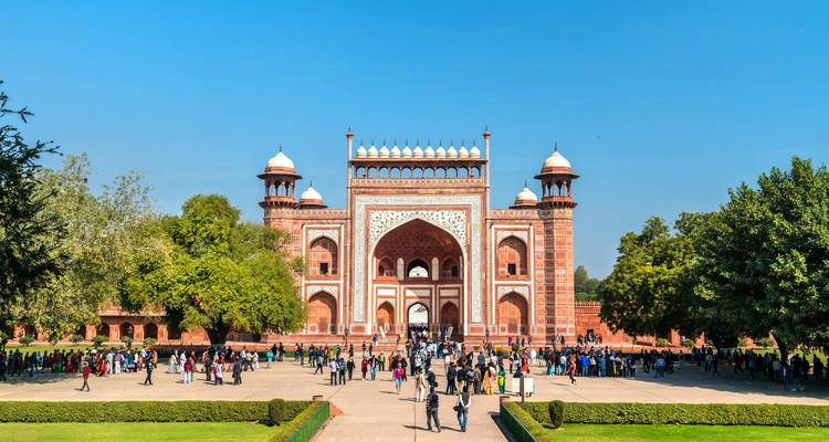 Eingang zum Roten Fort mit Menschen und Grün.