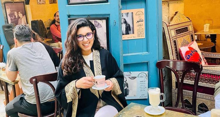 Mujer disfrutando café en un ambiente de cafetería tradicional.