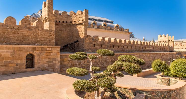 Restored stone walls, arches and a historic cannon in Baku’s Inner City under a clear blue sky.
