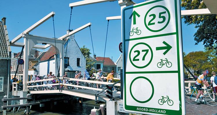 Cyclistes traversant un pont avec des panneaux directionnels.