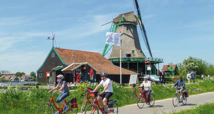 Des cyclistes passant devant un moulin à vent par une journée ensoleillée.