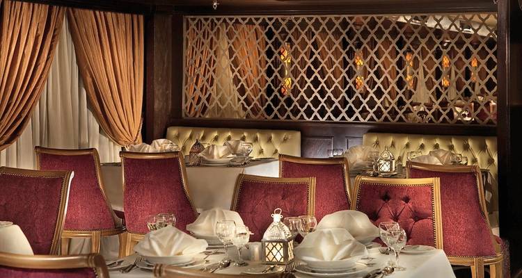 Salle à manger luxueuse avec des chaises rouges et un éclairage tamisé.