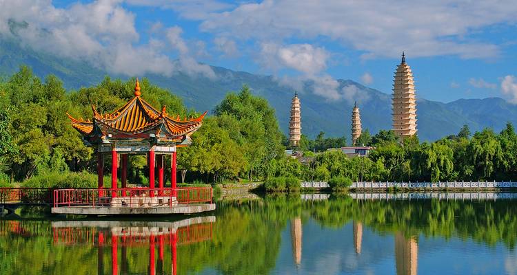 Pagodas reflected in a serene water body surrounded by lush greenery.