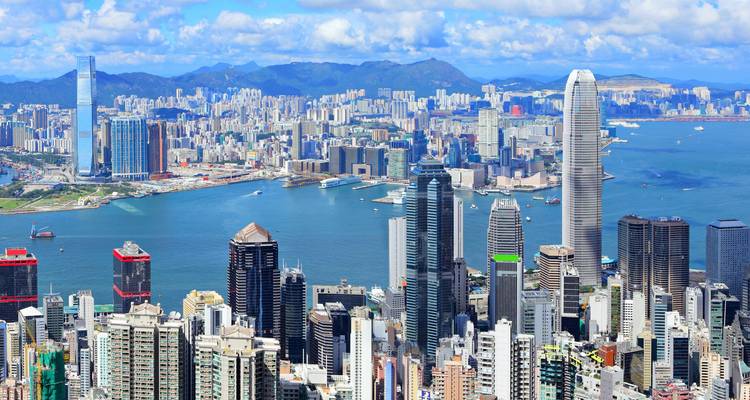 Panoramablick auf eine moderne Stadtskyline mit Hafen und Bergen.